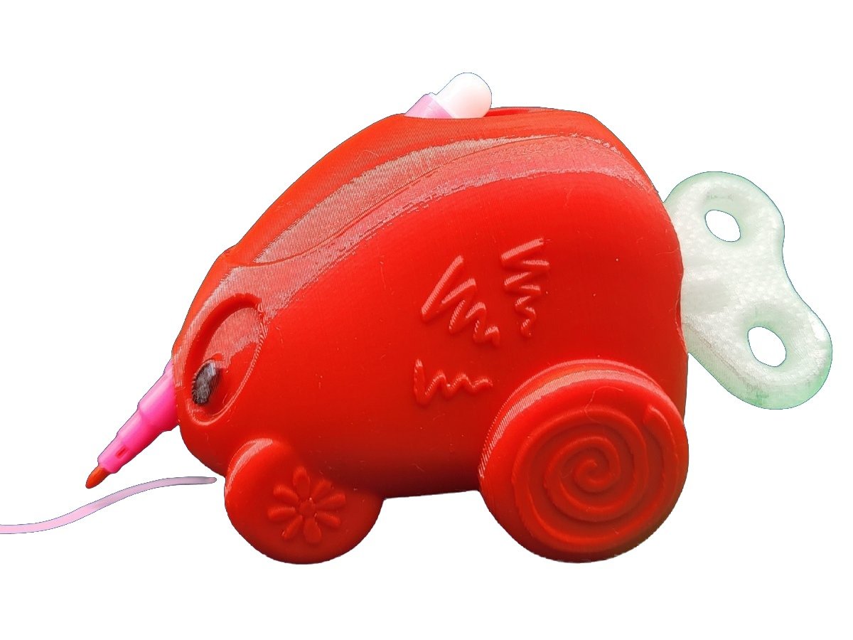A red Dexte, an art tool shaped like a small car, with a pink marker through it drawing a line.